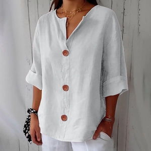 Detail of white linen V-neck blouse featuring brown buttons and rolled mid-length sleeves