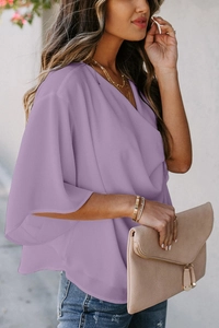 Outdoor shot of loose-fit light purple V-neck chiffon top with draped sleeves
