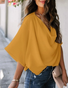 Detail of elegant ginger yellow chiffon top featuring a draped neckline and loose fit
