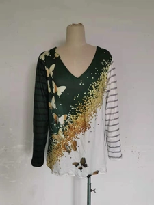 Dettaglio della maglia asimmetrica con scollo a V, stampa a farfalla e design a righe