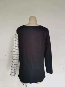 Dettaglio di una maglietta nera a maniche lunghe con design patchwork a righe grigie