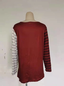 Dettaglio di maglia a maniche lunghe con strisce asimmetriche rosse e grigie