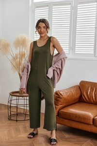 Detail of loose olive green sleeveless jumpsuit paired with a pink knit cardigan