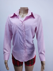 Dettaglio camicia rosa a maniche lunghe con chiusura a bottoni e taschino sul petto