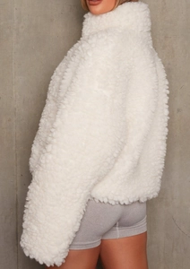Detail view of white teddy plush jacket featuring windproof high collar and fluffy texture
