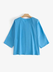 Détail de la texture du haut bleu clair à manches 3/4 avec rayures en lin et col rond