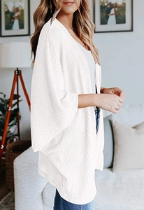 Detaillierte Waffelstrick-Textur an weißer Damen-Strickjacke mit Fledermausärmeln