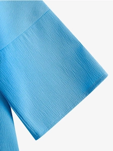 Vue macro de la texture du tissu crêpe bleu ciel et coutures nettes sur le haut à manches 3/4