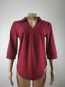 Detalle de blusa de gasa granate con cuello en V, mangas 3/4 y diseño de bajo curvo