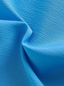 Détail macro du tissu crêpe bleu royal montrant la texture fine et la qualité de la chemise
