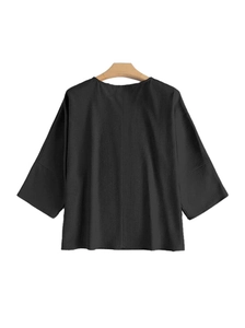 Détail du haut noir à col rond montrant la texture gaufrée sur un cintre en bois