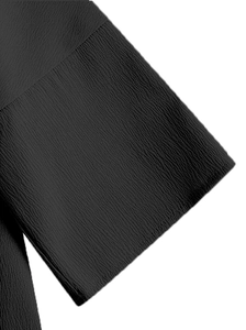 Gros plan d'une blouse noire montrant le tissu crêpé texturé et le grain vertical léger