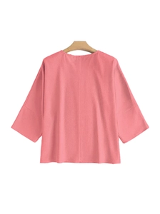 Détail du chemisier rose à manches 3/4 montrant le tissu texturé et l'encolure ronde