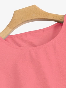 Détail de la blouse rose corail à col rond montrant la texture du tissu et les coutures