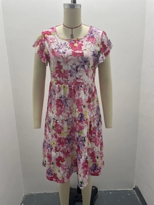 Detail of pink floral print dress showing round neck, ruffle sleeves and tiered skirt texture