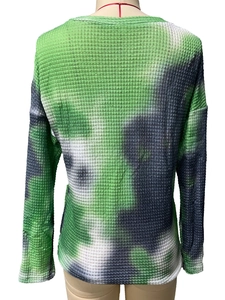 Close-up of green tie-dye waffle knit fabric texture on long sleeve loose sports top