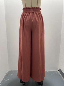 Detail of high waisted wide leg trousers in terracotta with elastic ruffled waistband