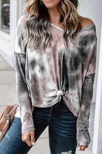 Close-up of tie-dye waffle knit texture and knotted hem detail on V-neck sweatshirt