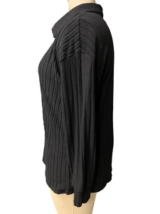 Dettaglio della maglia nera a coste e del collo alto su questa maglia ampia a maniche lunghe