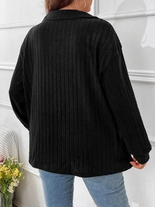 Dettaglio della trama a costine verticali su una maglia nera a maniche lunghe con scollo a V