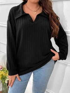 Dettaglio di un top nero in maglia a costine con scollo a V, colletto polo e trama a righe