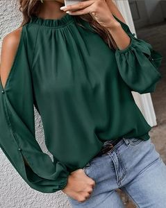 Detail of dark green cold-shoulder blouse with ruffled neckline and decorative sleeve buttons