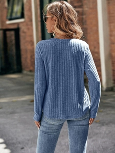 Vista exterior de una mujer con top de punto azul de manga larga y pantalones vaqueros