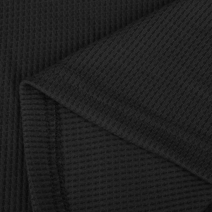 Nahaufnahme von schwarzem Waffelstrickstoff mit Textur und Doppelnaht am Saum