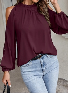 Detail of cold shoulder design and ruffled neckline on burgundy long sleeve blouse