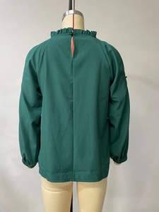 Close-up back view of dark green top with ruffled high neck and teardrop button closure