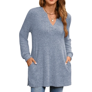 Dettaglio della tunica in maglia azzurra con scollo a V, maniche lunghe e tasche laterali