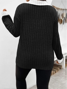 Dettaglio della trama a costine e cuciture grigie a contrasto sul retro di un top in maglia nera