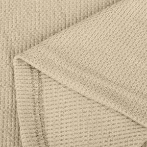 Makroaufnahme von hellkhakifarbener Waffelstrickstruktur mit präziser Nahtverarbeitung