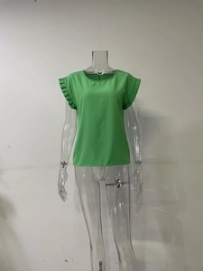 Detalle de elegantes mangas plisadas en una blusa verde fruta brillante con cuello redondo