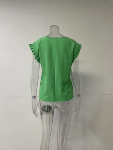 Detalle de la blusa verde hierba de manga corta con puños plisados y tejido ligero