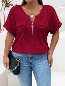 Detail of red ribbed V-neck top with zipper closure and decorative pocket flaps