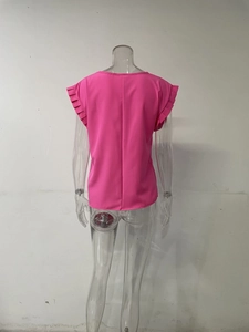 Detalle de los puños plisados multicapa en una blusa fucsia de manga corta y cuello redondo