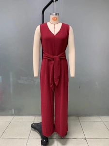 Detail of burgundy V-neck jumpsuit featuring crinkled texture fabric and waist tie belt