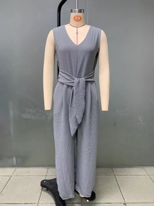 Detailed macro view of the grey V-neck jumpsuit featuring fine pleated fabric texture