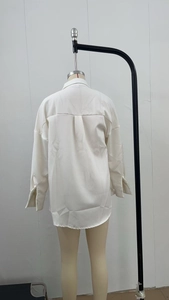 Detail view of the back of a white satin blouse with pleats and curved hemline