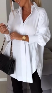 Close-up of the elegant curved hem and smooth fabric of the white oversized shirt