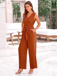 Detail of elegant caramel V-neck sleeveless wide leg jumpsuit with waist tie in resort setting