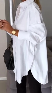 Detail of white oversized shirt featuring irregular curved hem and side split design