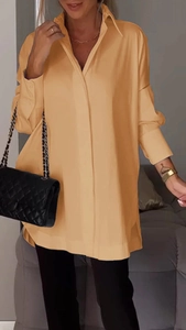 Detail of elegant ginger yellow long-sleeved shirt with side slits and hidden placket