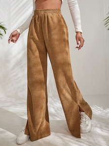 Detail of high waisted corduroy trousers featuring side slit hem and ribbed texture