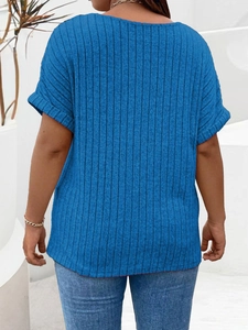 Back view of a loose blue ribbed knit T-shirt with rolled sleeves in a minimalist setting