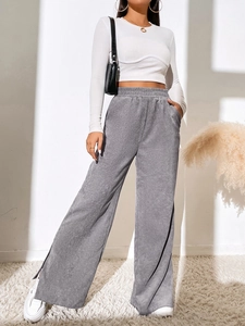 Detail of high-waist grey corduroy trousers with side slit hem and ribbed texture finish