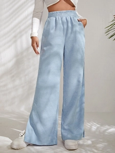 Detail of high waist corduroy trousers in sky blue with side slit hem and ribbed texture