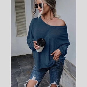 Détail du haut en maille bleu-gris montrant la coupe ample et le style épaule dénudée