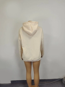 Detail view of cream oversized hoodie showing dropped shoulder and ribbed knit cuffs